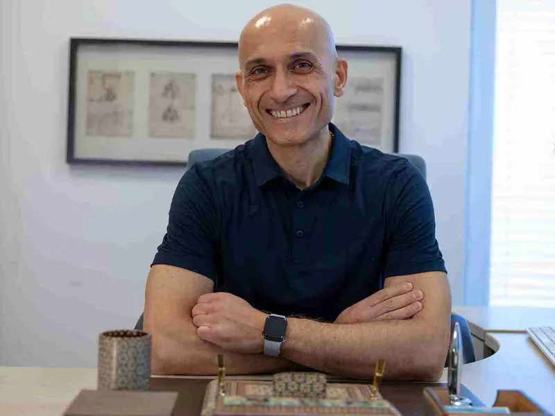 Dr. Dr. med. Mahmoud Salman smiling at his desk with his arms folded