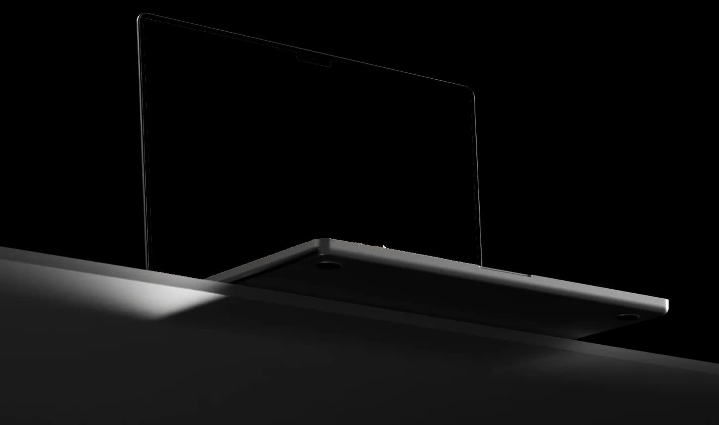 The HelloDevs website open on a laptop, seen from a low angle against an orange glow