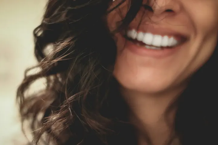 Close-up of a woman laughing with a relaxed jaw